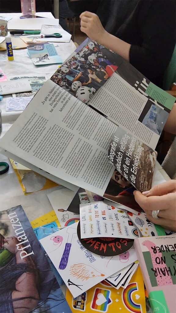 Ein Magazin ist aufgeschlagen - einige Seiten sind schon zerschnitten. Im Hintergrund ist ein Tisch voll mit Bastelmaterialien zu sehen.